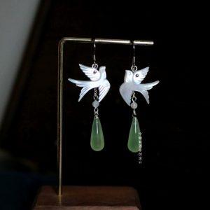 Delicate bird dangle earrings with a sparkling gemstone and a slim chain.